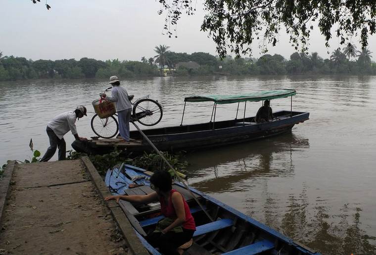 Cyclist riding off a river ferry in the Mekong Delta