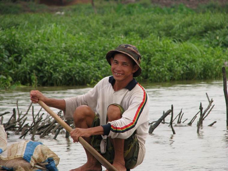 A wooden passenger boat crossing a wide branch of the Mekong